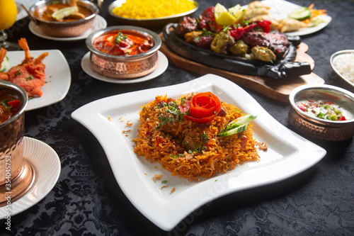 Table with typical Indian dishes, Biryani, chicken curry, tandoori, tikka masala, korma, rice pilaf.