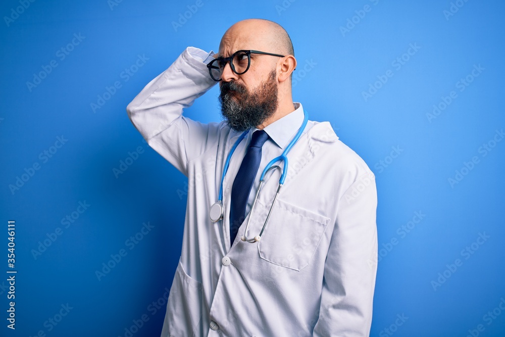 Handsome bald doctor man with beard wearing glasses and stethoscope over blue background confuse and wondering about question. Uncertain with doubt, thinking with hand on head. Pensive concept. Handsome bald doctor man with beard wearing glasses and stethoscope over blue background confuse and wondering about question. Uncertain with doubt, thinking with hand on head. Pensive concept.