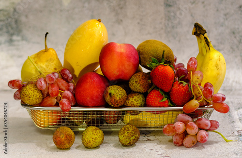 Assortment of exotic fruits in metal basket isolated on white view