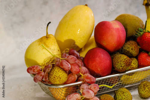 Assortment of exotic fruits in metal basket isolated on white view