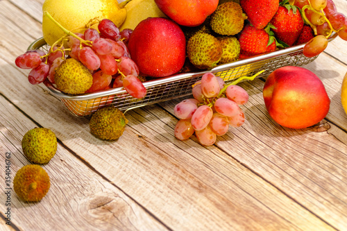 Assortment of exotic fruits in metal basket isolated on wood view