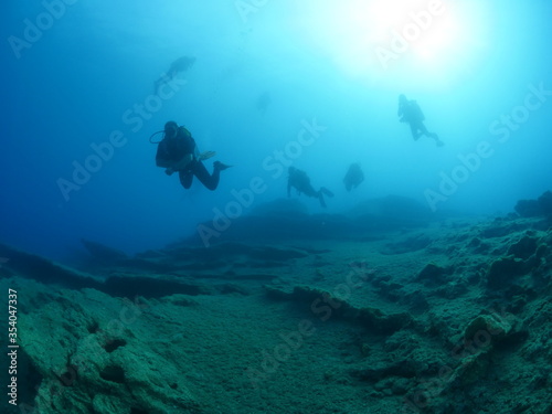 scuba divers exploring scenery underwater sun beams and rays sun shine silhouette ocean scenery © underocean