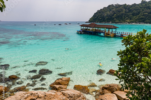 Snorkelling people in turquoise water on tropical Malaysian island Perhentian Besar