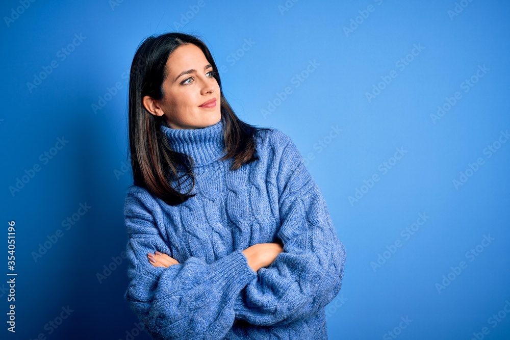 Young brunette woman with blue eyes wearing casual turtleneck sweater looking to the side with arms crossed convinced and confident Young brunette woman with blue eyes wearing casual turtleneck sweater looking to the side with arms crossed convinced and confident