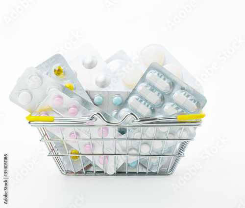 Various Pills in blisters are in a small shopping basket on a white background. Sale of drugs in stores and pharmacies. Health and medicine.