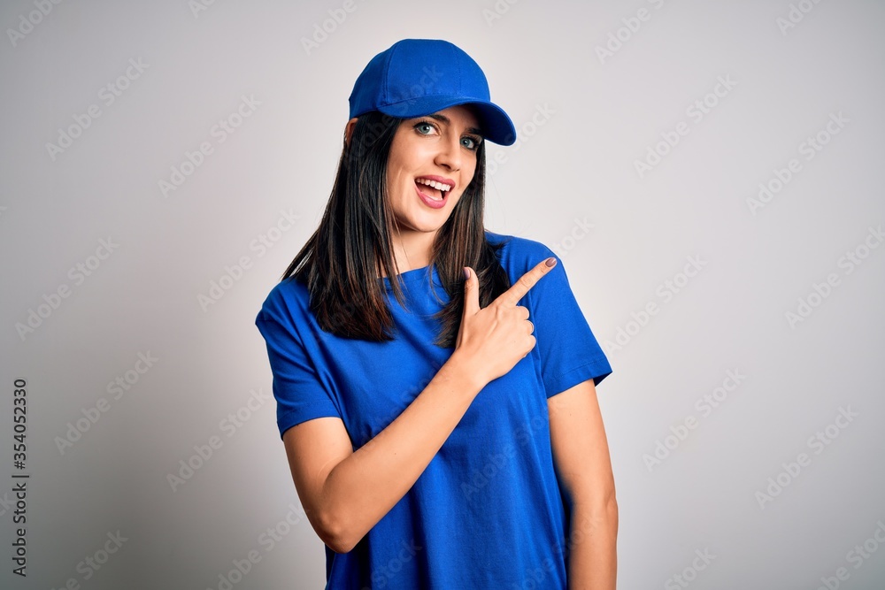 Young delivery woman with blue eyes wearing cap standing over blue background cheerful with a smile of face pointing with hand and finger up to the side with happy and natural expression on face Young delivery woman with blue eyes wearing cap standing over blue background cheerful with a smile of face pointing with hand and finger up to the side with happy and natural expression on face