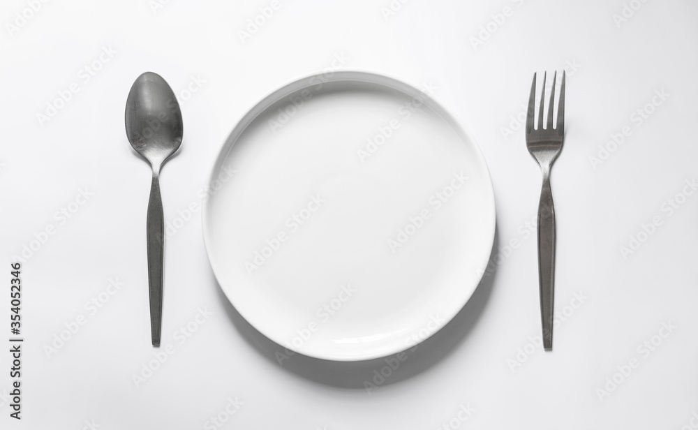 Ceramic round dish with silver fork and spoon, on white table