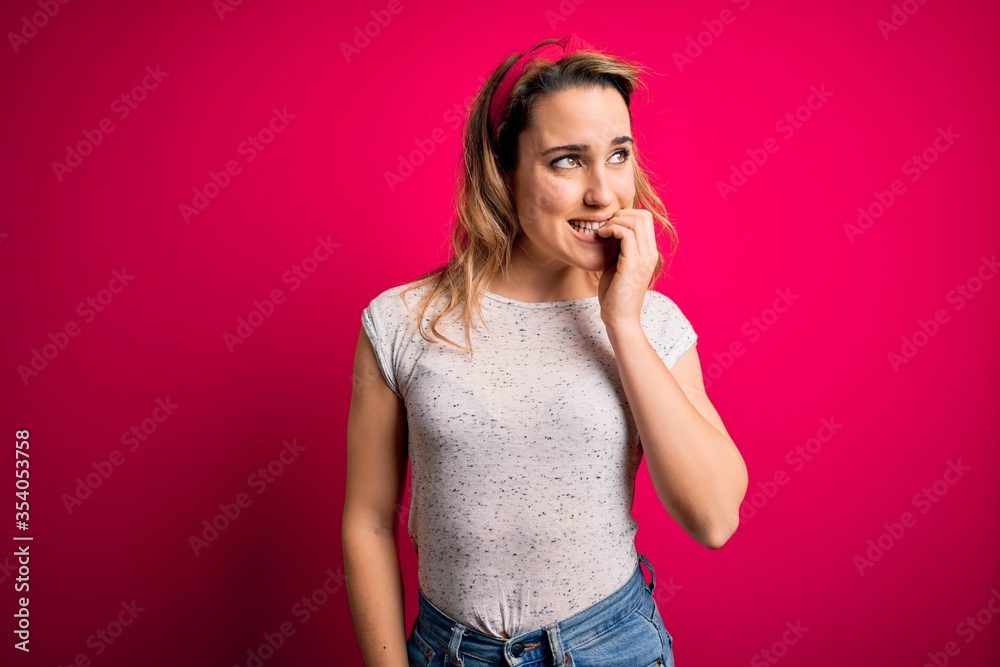 Young beautiful blonde woman wearing casual t-shirt standing over isolated pink background looking stressed and nervous with hands on mouth biting nails. Anxiety problem. Young beautiful blonde woman wearing casual t-shirt standing over isolated pink background looking stressed and nervous with hands on mouth biting nails. Anxiety problem.