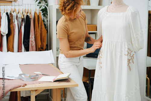 Image of a small business. She tries on a dress on a mannequin