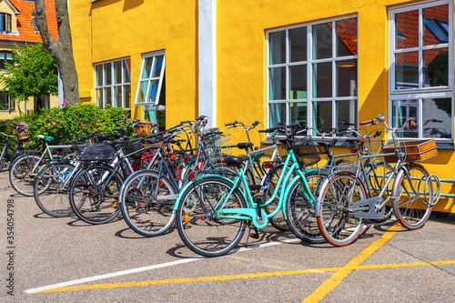 Many bicycles parked in front of a yellow house. Copenhagen. Denmark. Bicycles are one of the main means of transportation .. © vallerato
