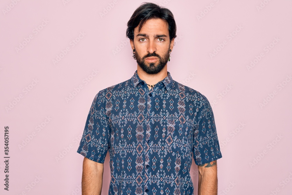 Young handsome hispanic bohemian man wearing hippie style over pink background Relaxed with serious expression on face. Simple and natural looking at the camera. Young handsome hispanic bohemian man wearing hippie style over pink background Relaxed with serious expression on face. Simple and natural looking at the camera.