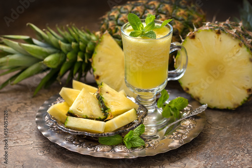 Ripe pineapples (Ananas comosus) and a glass of fresh juice on a vintage dish