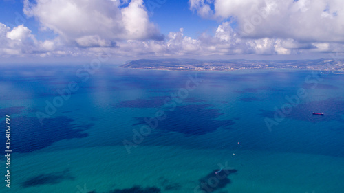 Beautiful cloud shadows on the blue water of the Tsemess Bay. Novorossiysk in the background