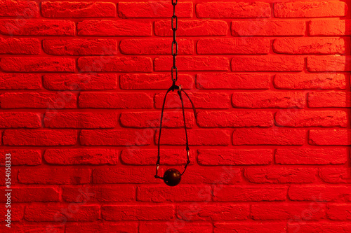 Black ball gag in mouth on red brick wall