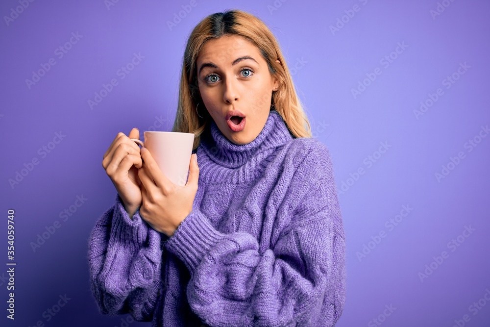 Obraz premium Young beautiful blonde woman drinking cup of coffee over isolated purple background scared in shock with a surprise face, afraid and excited with fear expression