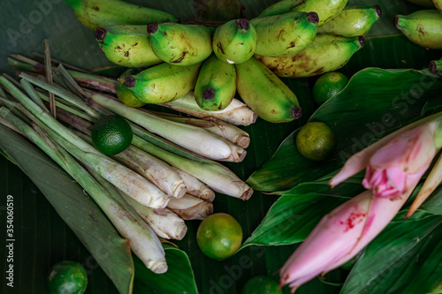 Asian food ingredients such as lemongrass, calamansi, tumeric leaves, torch lily and bananas on a banana leaf background.