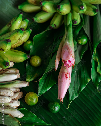 Asian food ingredient with bunga kantan or torch lily, calamansi, lemongrass, tumeric leaves and bananas on a banana leaf background.