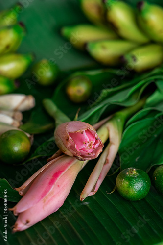Asian food ingredient with bunga kantan or torch lily, calamansi, lemongrass, tumeric leaves and bananas on a banana leaf background.