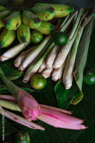 Asian food ingredient lemongrass, calamansi, tumeric leaves and bananas on a banana leaf background.