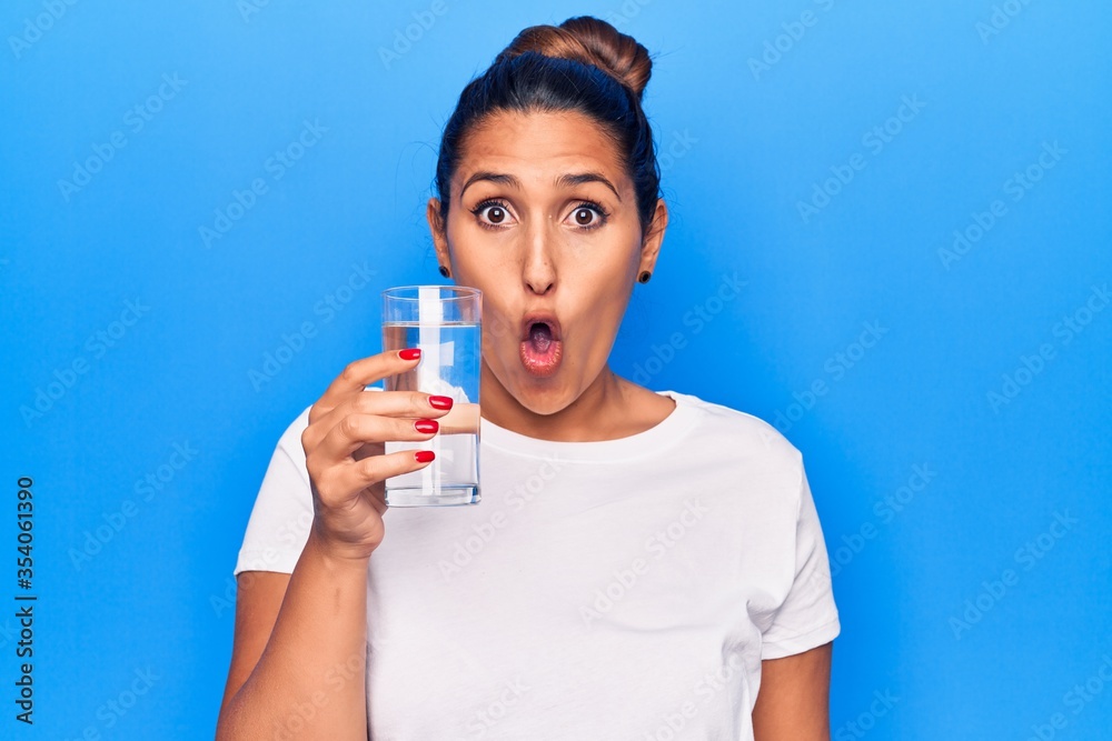 Young beautiful brunette woman drinking glass of water scared and amazed with open mouth for surprise, disbelief face Young beautiful brunette woman drinking glass of water scared and amazed with open mouth for surprise, disbelief face