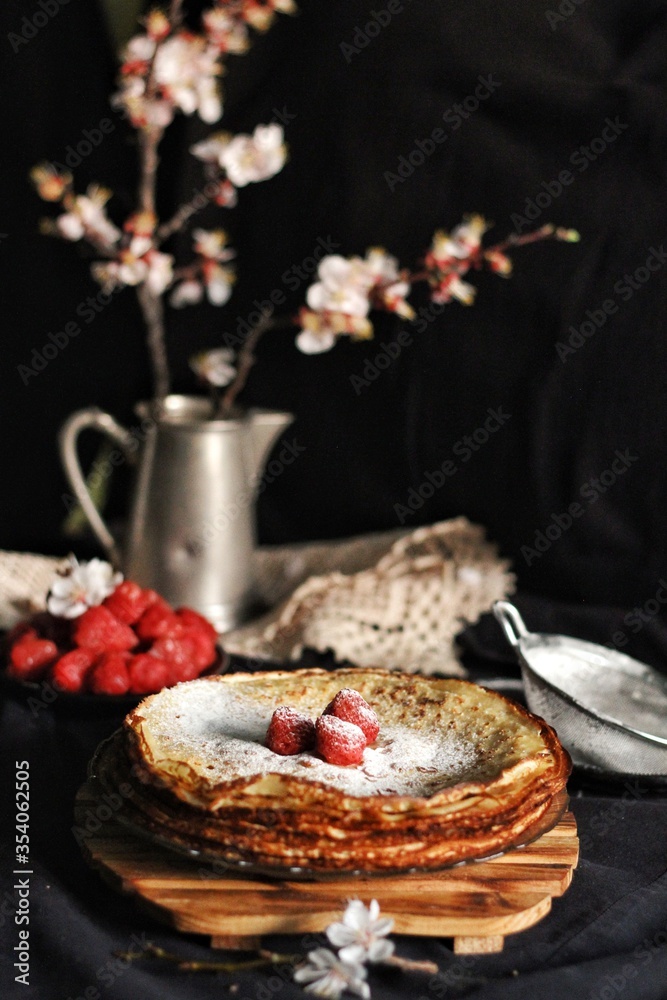 Thin crepes, pancakes or blinis on slate isolated on black background, tasty breakfest