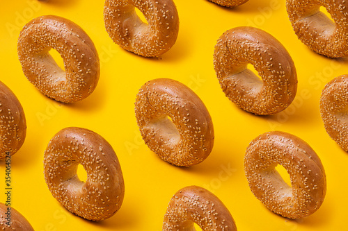 Slika na platnu Colorful pattern with round bread bagels with sesame seeds on yellow background