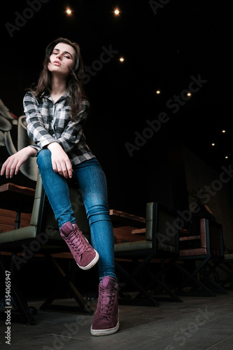 Beautiful brunette model girl posing at the dark background of interior cafe