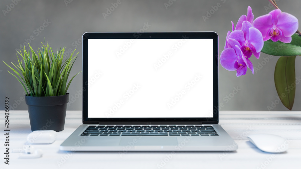 Fototapeta premium Laptop computer white blank screen on work table front view. Copy space, home and office workspace concept, laptop mockup.
