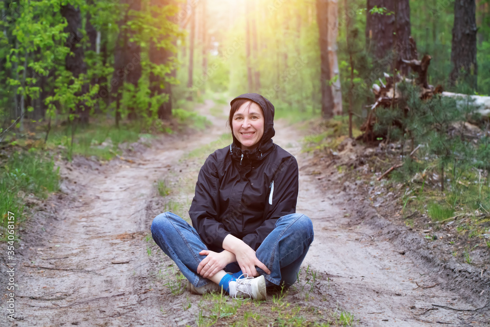 Man in the forest. A middle-aged woman sits on a forest road. Man in the forest. A middle-aged woman sits on a forest road.