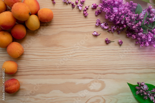 Natural background: bright apricots and lilac branches lie on a wooden table