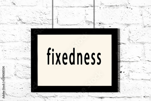 Fotografie Black frame hanging on white brick wall with inscription fixedness