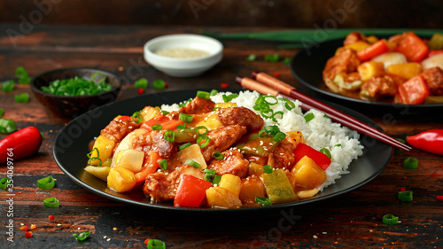Pineapple and Chicken in sweet and sour sauce with bell pepper, rice and spring onion on wooden table