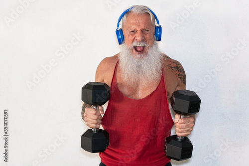 Senior man doing gym workout with dumbbells while wearing face protective mask during Coronavirus isolation quarantine - Fitness, sport and healthy elderly lifestyle - Focus on face