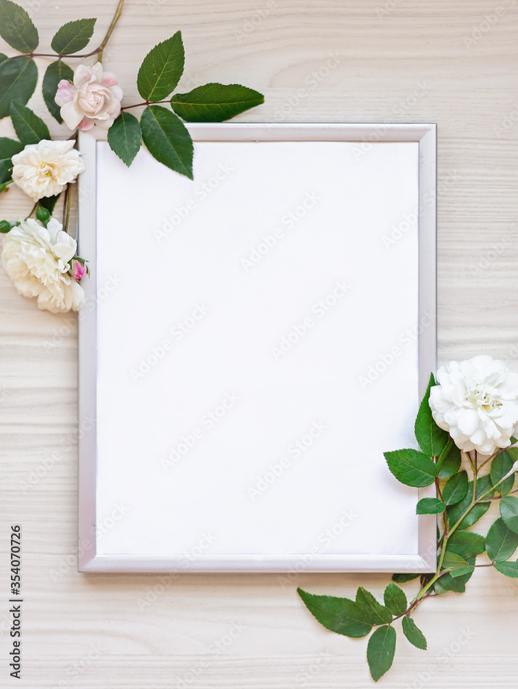photo frame decorated with green leaves and rose flowers on beige pastel background. empty white space for text. mock up with copy space. Flat lay. Greeting card concept