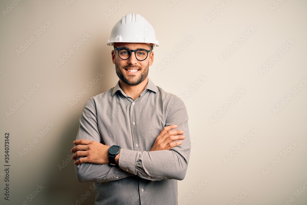 Young architect man wearing builder safety helmet over isolated background happy face smiling with crossed arms looking at the camera. Positive person. Young architect man wearing builder safety helmet over isolated background happy face smiling with crossed arms looking at the camera. Positive person.