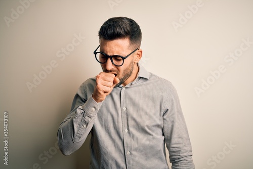 Young handsome man wearing elegant shirt and glasses over isolated white background feeling unwell and coughing as symptom for cold or bronchitis. Health care concept.