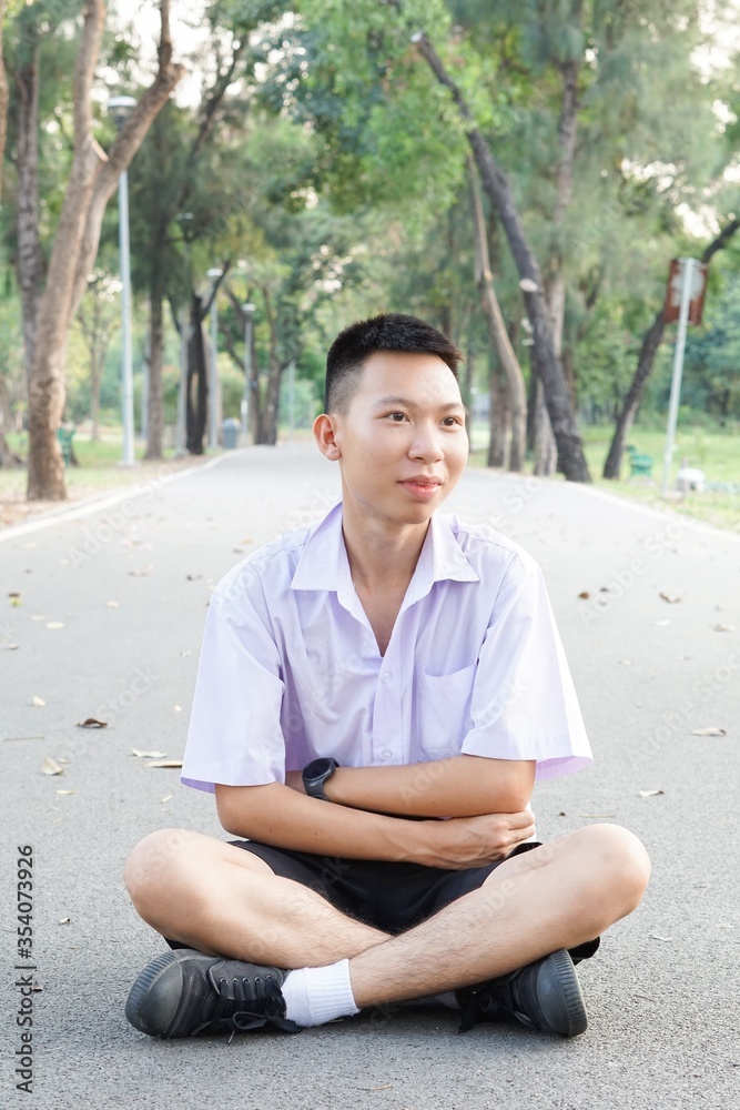 cute thai student in uniform sitting on road floor