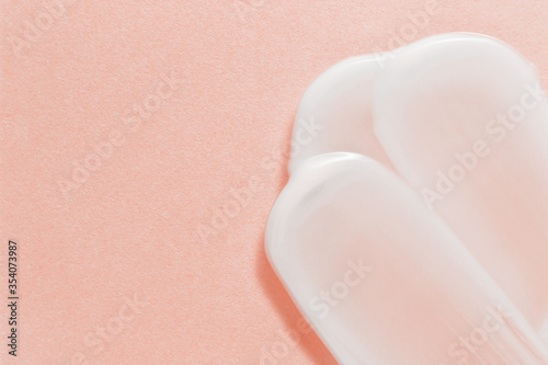 White cosmetic cream strokes on pink background. Skincare lotion face serum smear. Beauty product texture