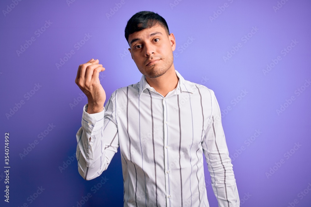 Naklejka premium Young handsome hispanic man wearing elegant business shirt standing over purple background Doing Italian gesture with hand and fingers confident expression