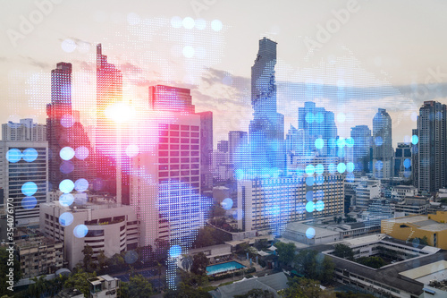 Multi exposure of Bangkok cityscape sunrise background and world map hologram. Concept of media networking.