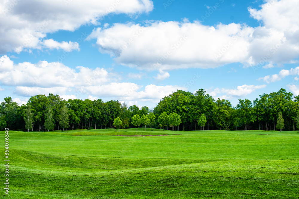 Empty golf course with trees in the background and blue sky with clouds.. Empty golf course with trees in the background and blue sky with clouds..