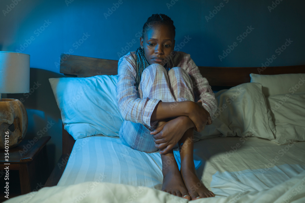 Obraz premium young sad and depressed black African American woman lying on bed at home unhappy and sleepless at night feeling overwhelmed suffering depression problem and insomnia