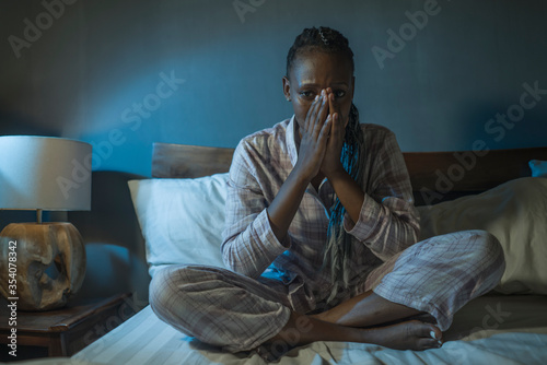 young sad and depressed black African American woman lying on bed at home unhappy and sleepless at night feeling overwhelmed suffering depression problem and insomnia