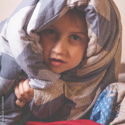 Funny portrait of huppy little cute child girl before bedtime under the blanket. photo