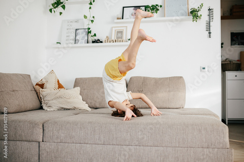 Beautiful little toddler tumbling on sofa at home. photo