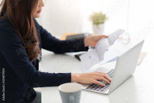 Worried Asian woman holding receipt bill and calculating family budget and monthly expense and Debt with laptop computer at home. Female having problem income and budget payment. Economic crisis