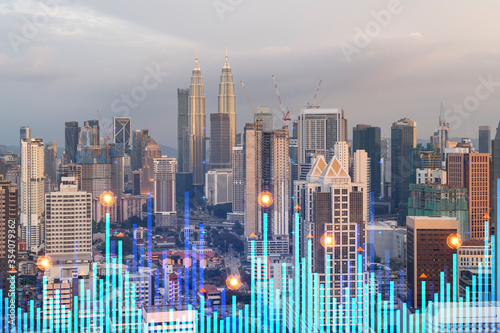 Market behavior graph hologram, sunset panoramic city view of Kuala Lumpur. KL is popular location to achieve financial degree in Malaysia, Asia. The concept of financial data analysis.