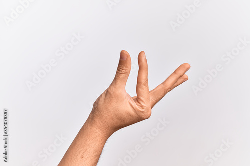 Hand of caucasian young man showing fingers over isolated white background picking and taking invisible thing, holding object with fingers showing space © Krakenimages.com