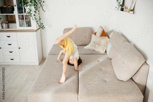 Photography Cute little toddler girl tumbling on sofa at home.