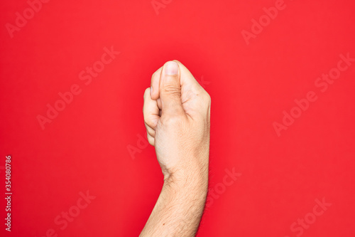 Hand of caucasian young man showing fingers over isolated red background holding blank space with thumb finger, business and advertising